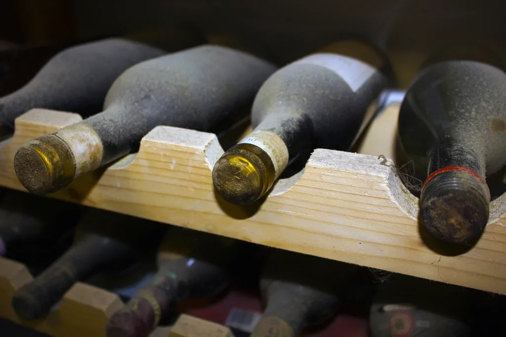 Bouteilles de vin couchées dans un casier en bois, bouchons cirés visibles